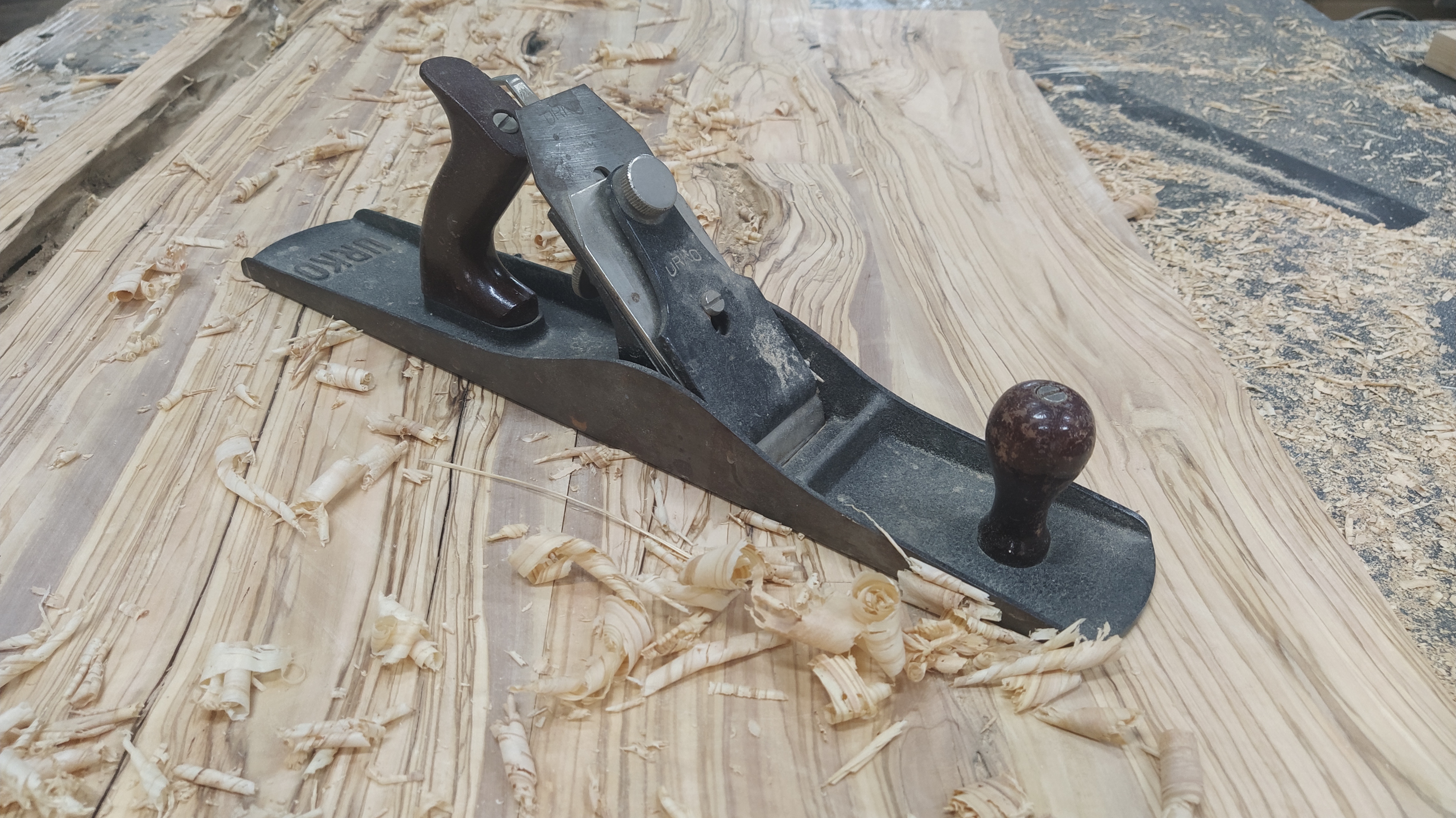 Cepillo manual y virutas sobre madera de olivo